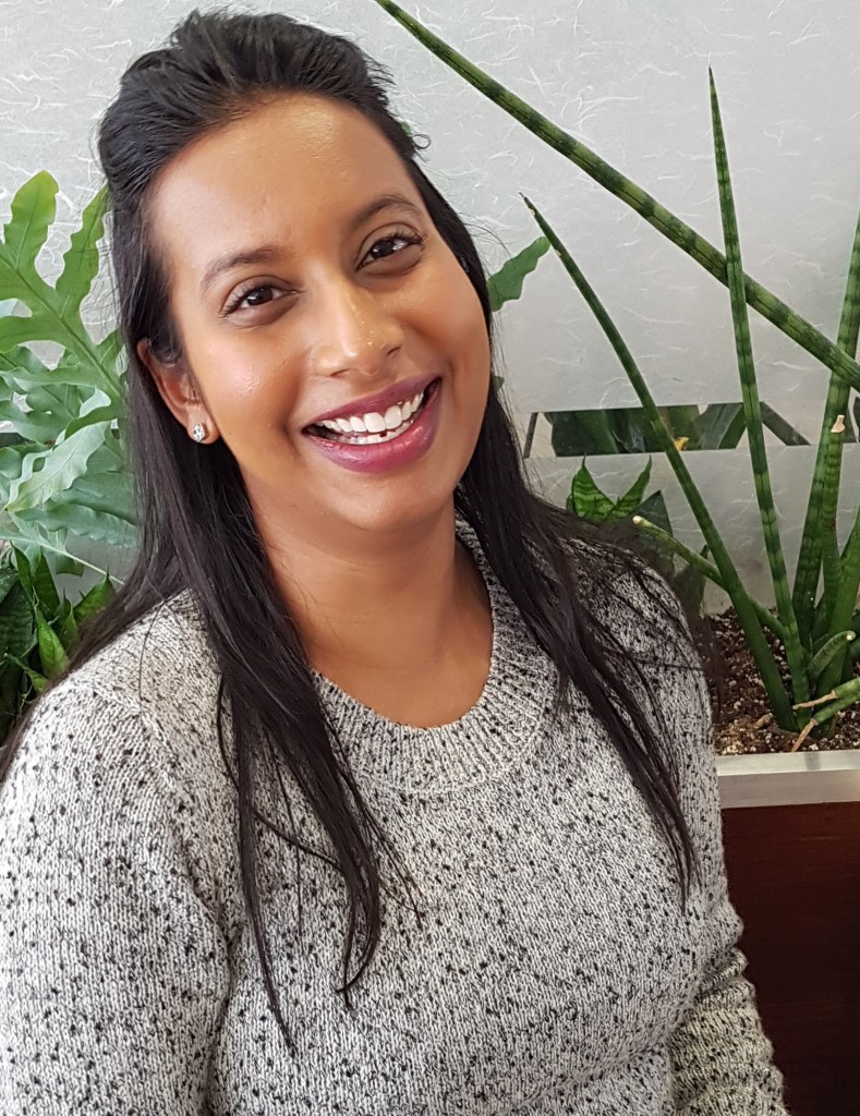 Usha Rajpal Cheddi is the Founder of Lettering by Usha. She is pictured wearing a grey knit shirt and a smile. Photo courtesy of: Usha Rajpal Cheddi.