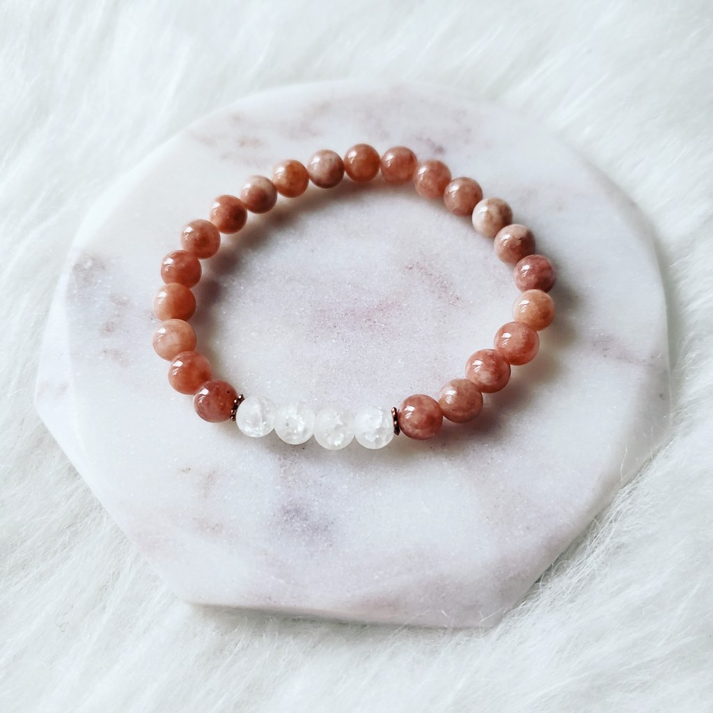 A Mashan Jade and Crackle Rock Quartz bracelet made by Trias. Majority of this bracelet is made with blush coloured stone beads and four white stones are in the middle. Photo by: Alvia Giash.